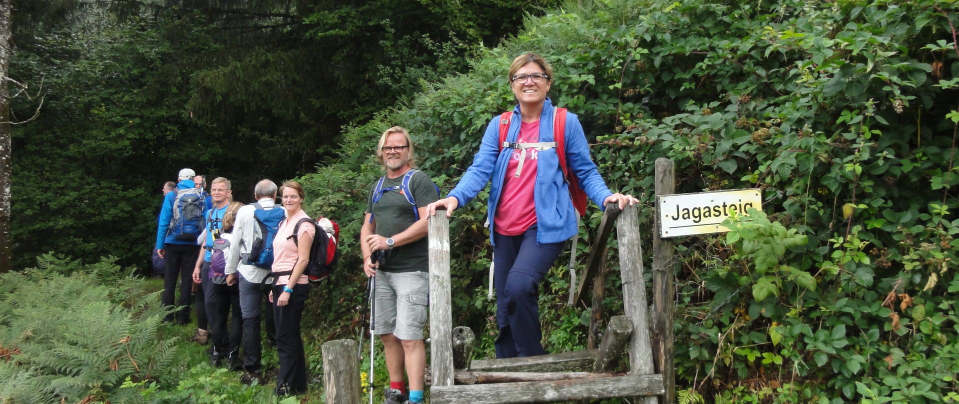 Lächelnde Wanderer auf dem Höhenwanderweg Neuhaus, umgeben von üppigem Grün und Wald