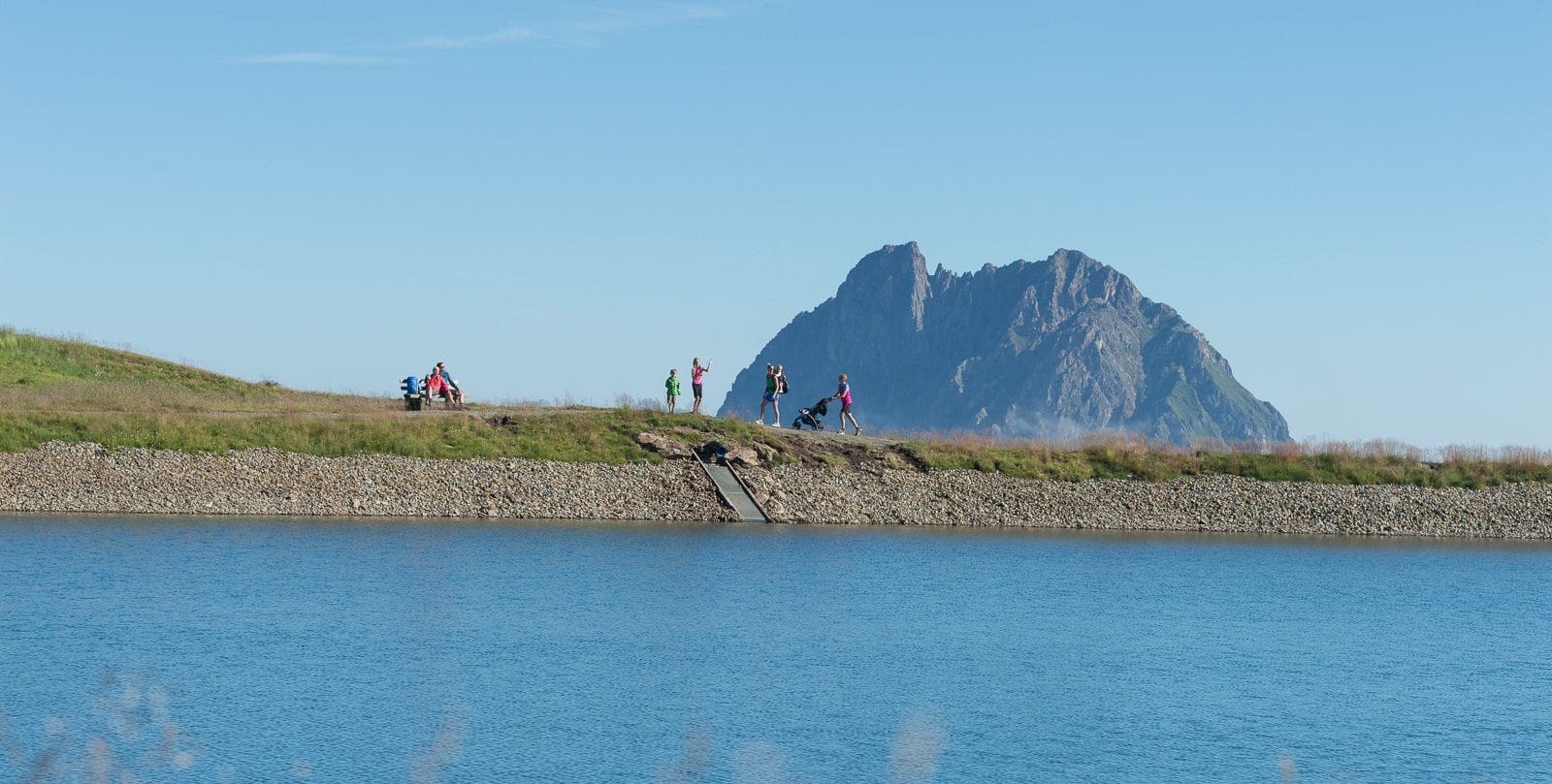 Wanderer bei sonnigem Wetter am Wildkogel Panoramaweg vor einem Speichersee