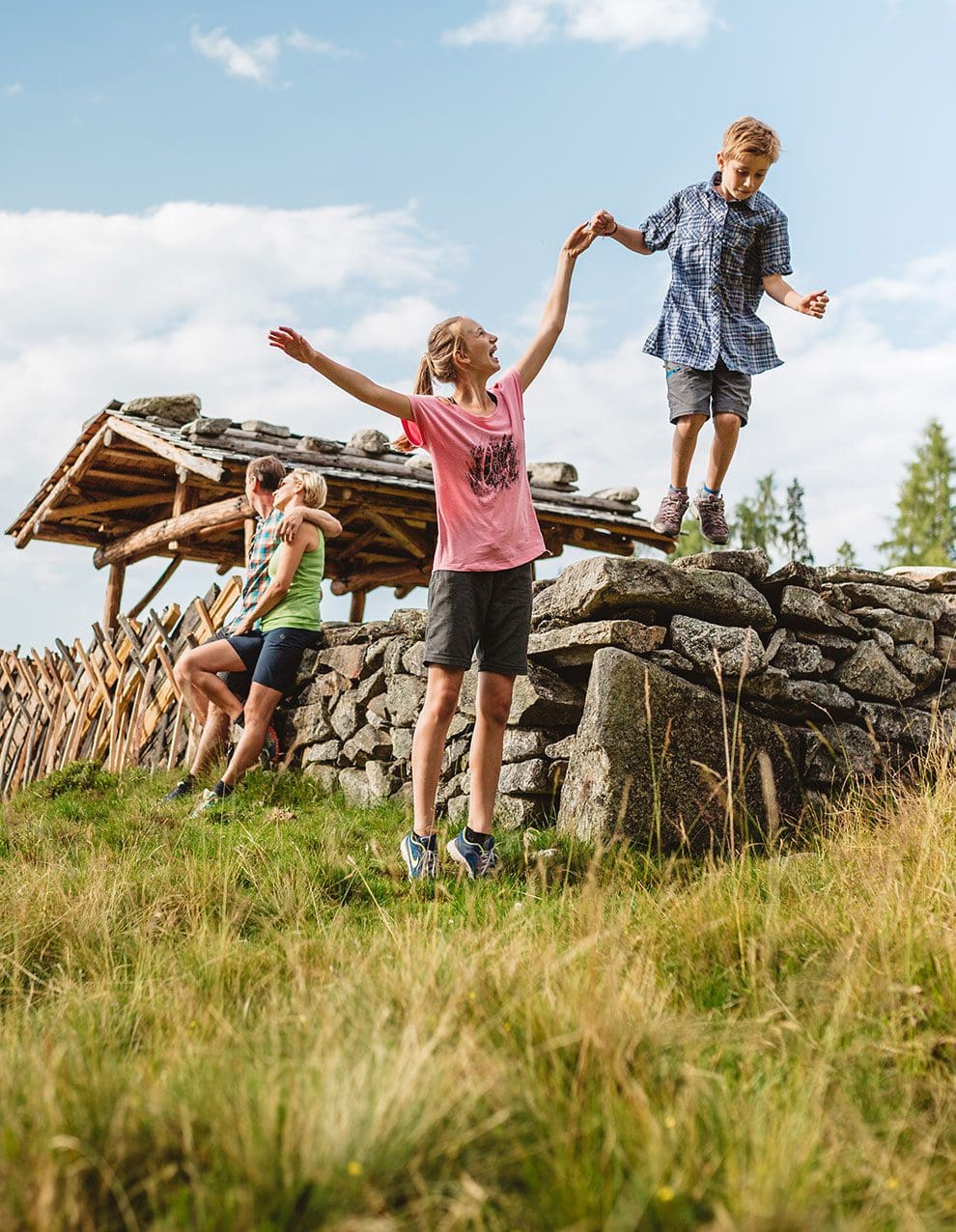 Kinder beim Spielen auf Steinen mit Eltern im Hintergrund in den Salzburger Bergen