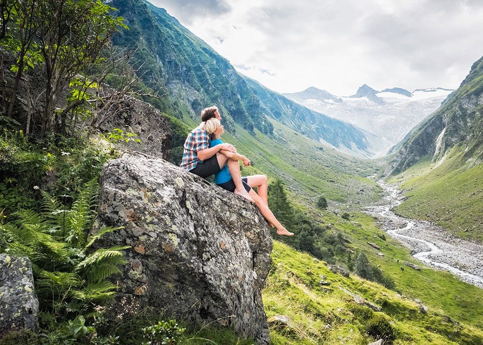 Paar genießt Ausblick auf Bach im Nationalpark Hohe Tauern