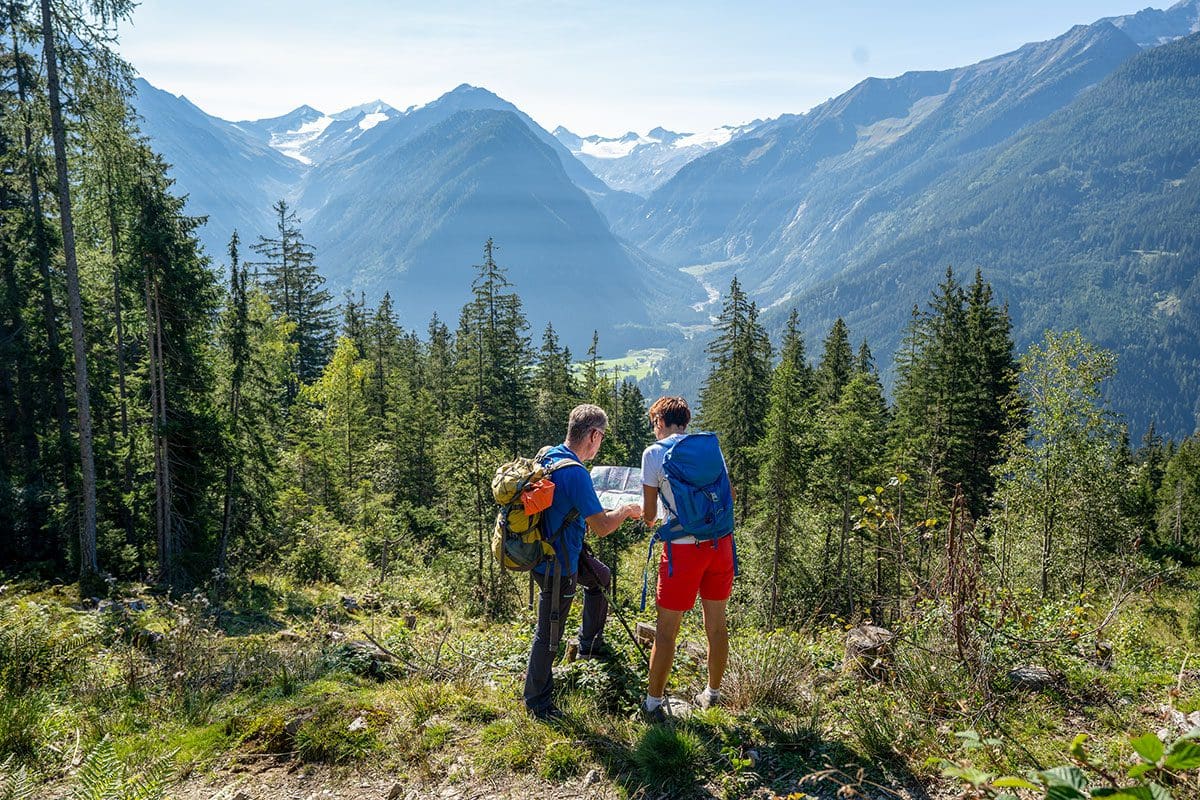 Paar schaut in eine Karte zur Orientierung mit Gebirge im Hintergrund